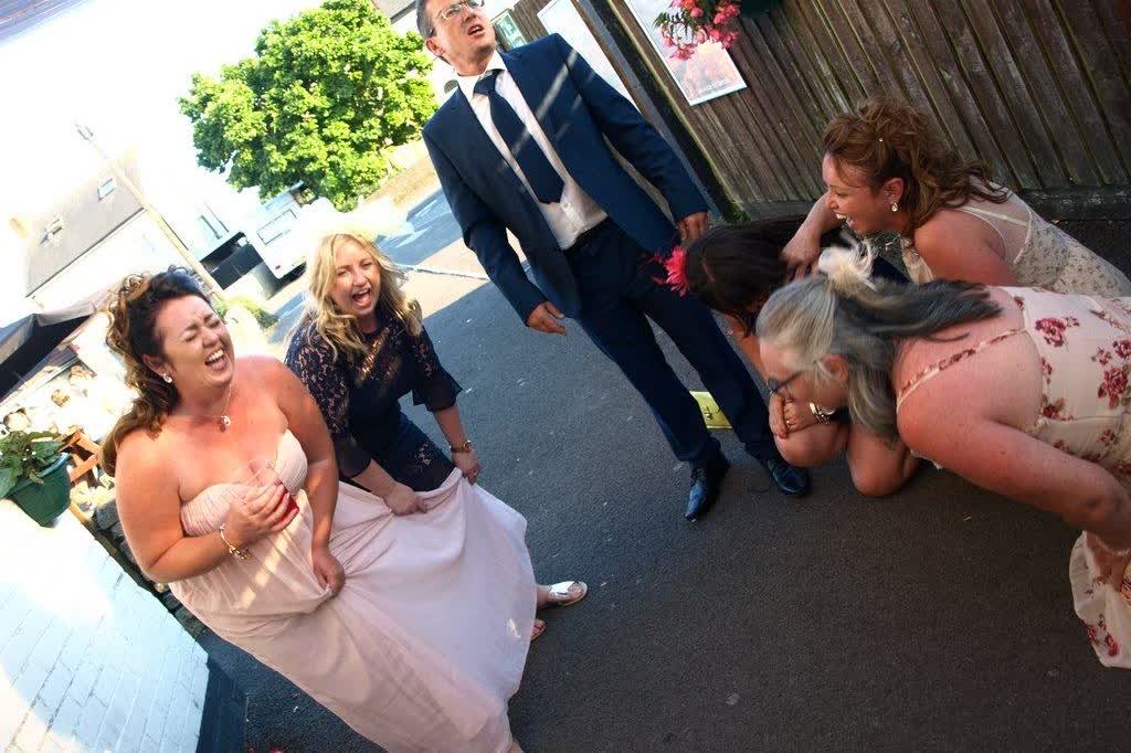 A group of wedding guests doubled up laughing at a comedy set.